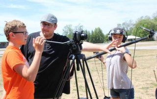 Film camp students around a camera